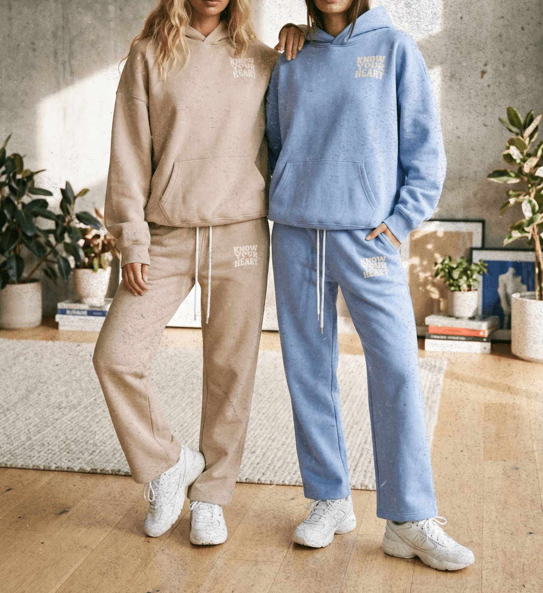 Two people wearing matching beige and blue tracksuits in a living room setting.