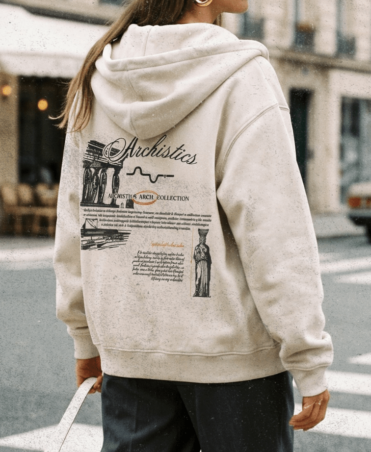 Person wearing a beige hoodie with graphics and text, walking on a city street.