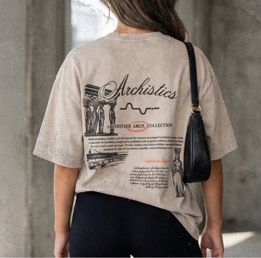 Person wearing a beige t-shirt with text and graphics, black shorts, white sneakers, and carrying a black handbag.