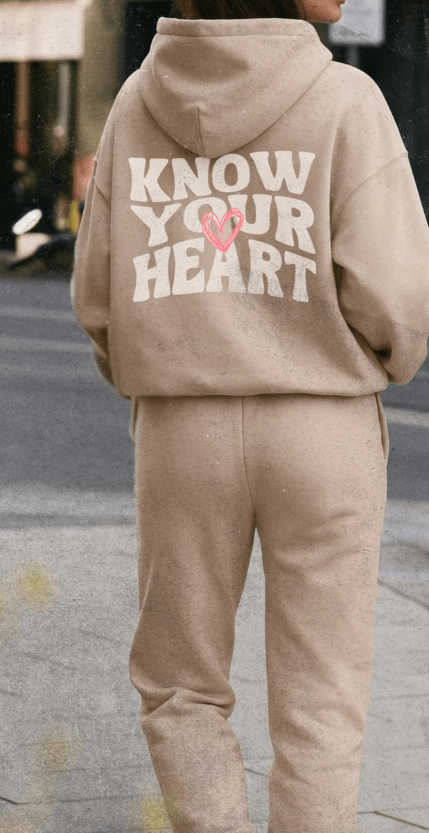 Person wearing a beige hoodie with 'KNOW YOUR HEART' text on the back.