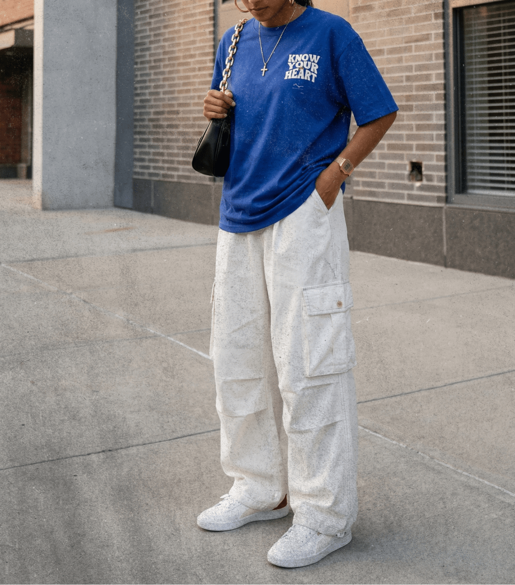 Person wearing a blue t-shirt and white cargo pants standing on a sidewalk.