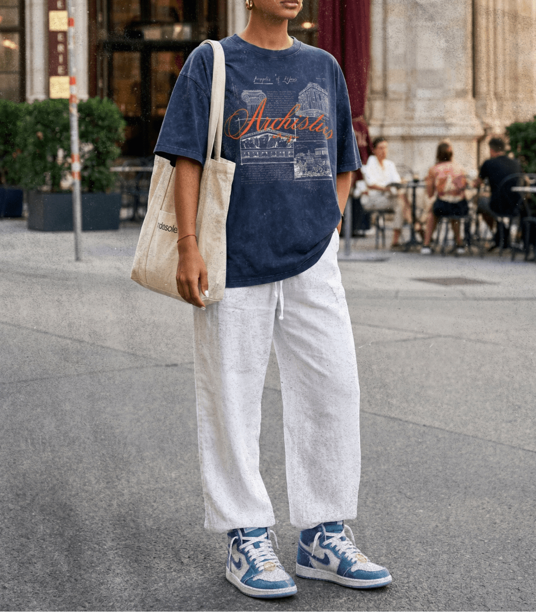 Person wearing a blue graphic t-shirt, white pants, and blue sneakers in an urban setting.