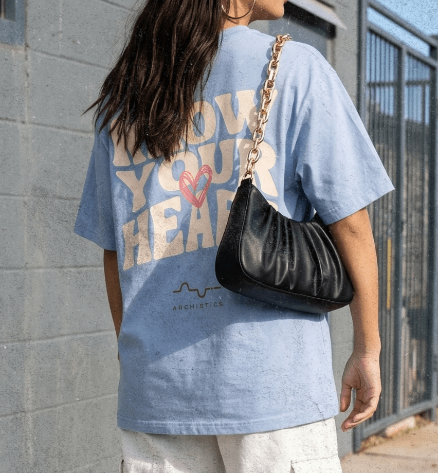 Person wearing a blue graphic t-shirt and white cargo pants standing on a sidewalk.