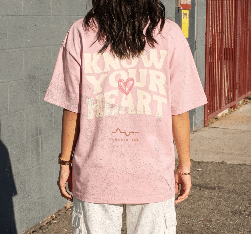 Person wearing a pink t-shirt with text and graphics, standing on a street.