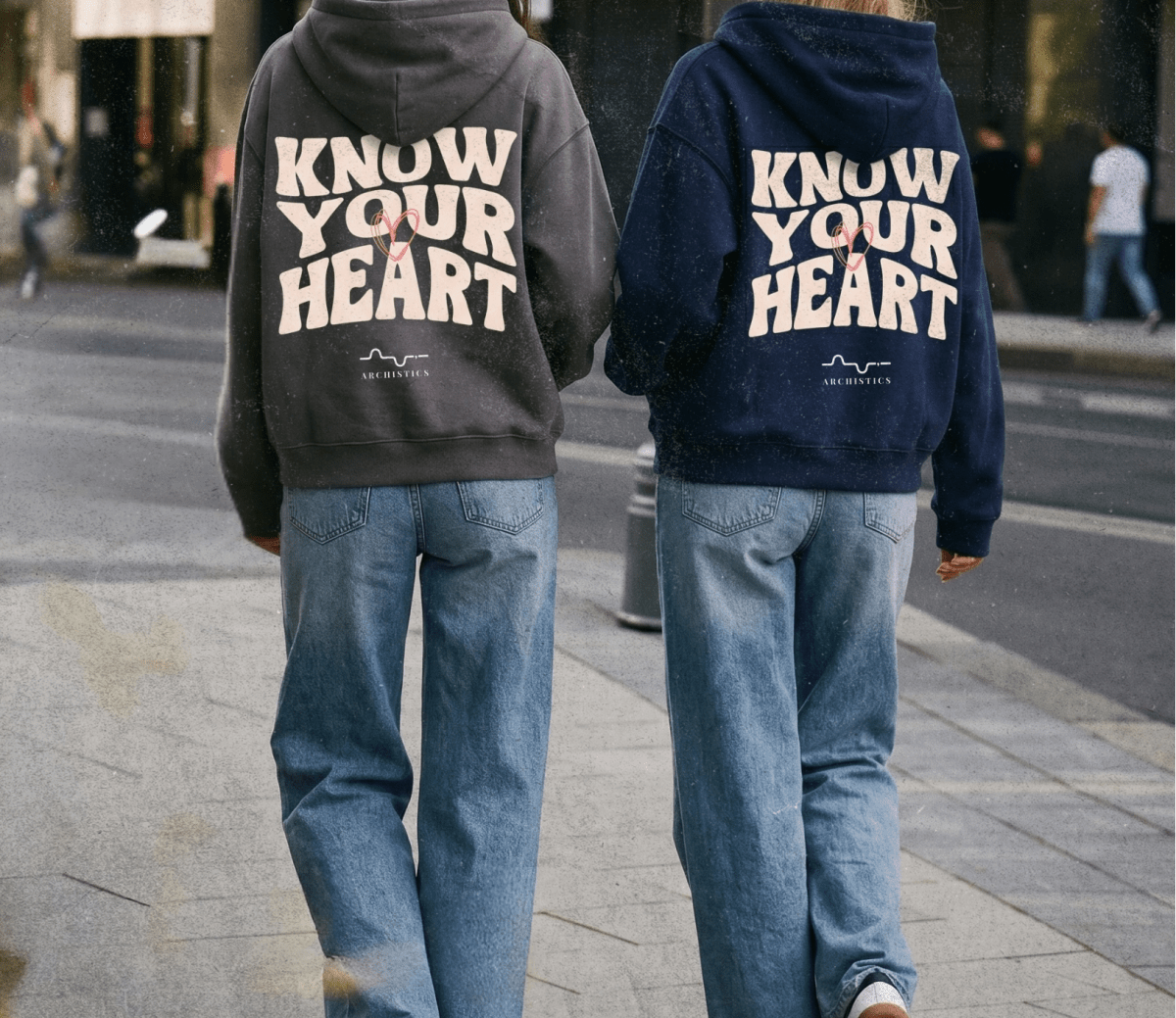 Two people wearing hoodies with 'Know Your Heart' text on a city street.