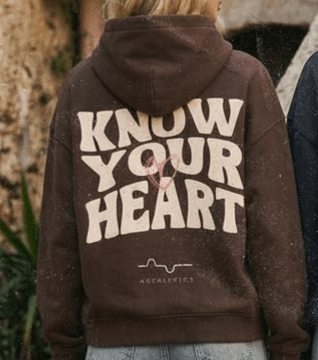 Two people wearing hoodies with 'Know Your Heart' text on the back, standing on stone steps.