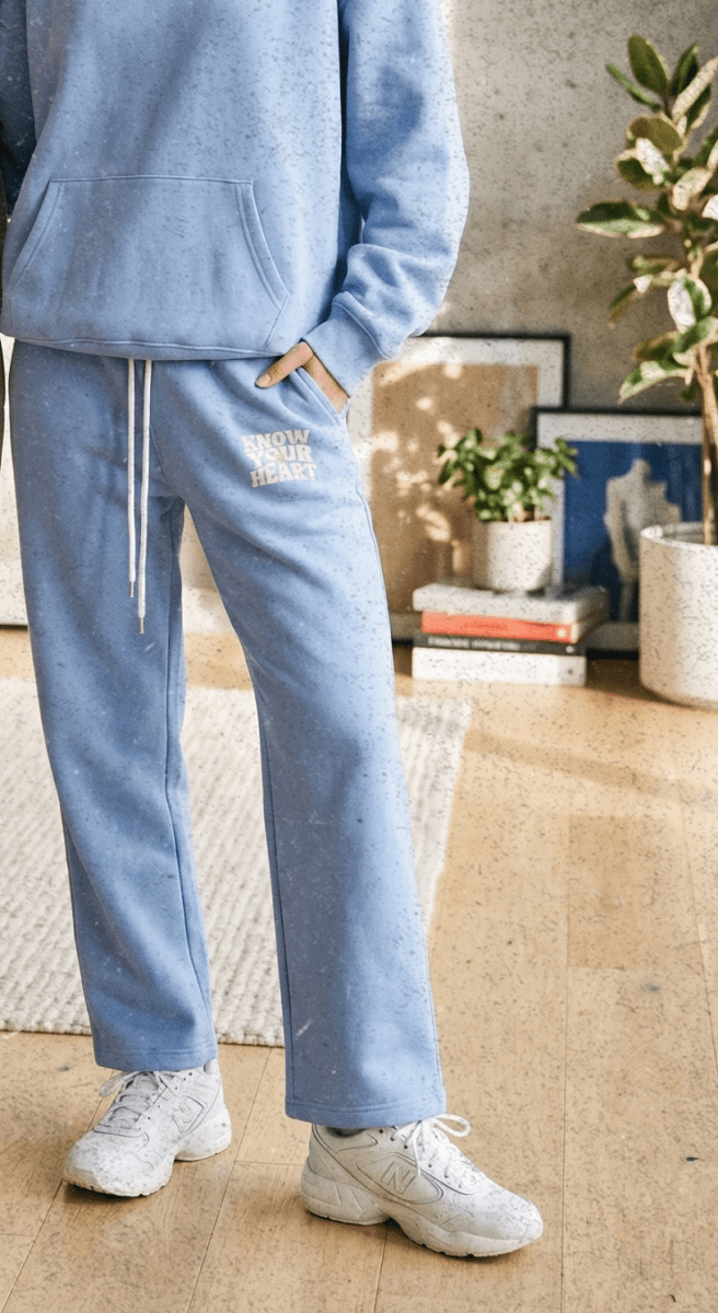 Two people wearing matching beige and blue tracksuits in a living room setting.