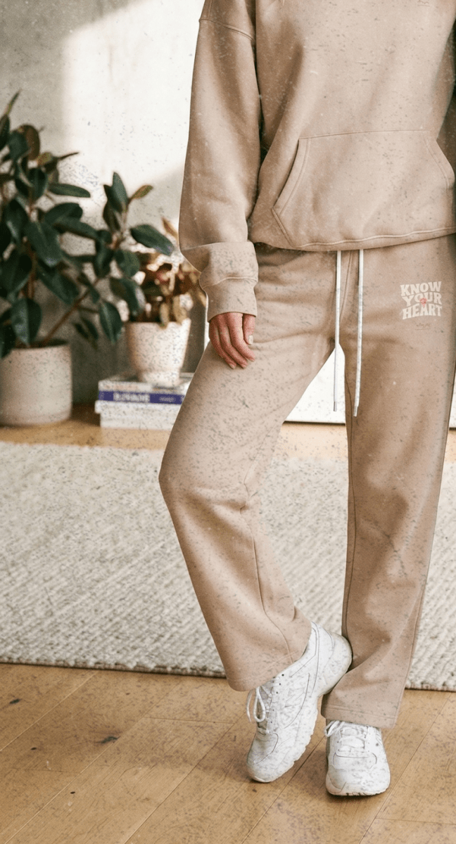 Two people wearing matching beige and blue tracksuits in a living room setting.