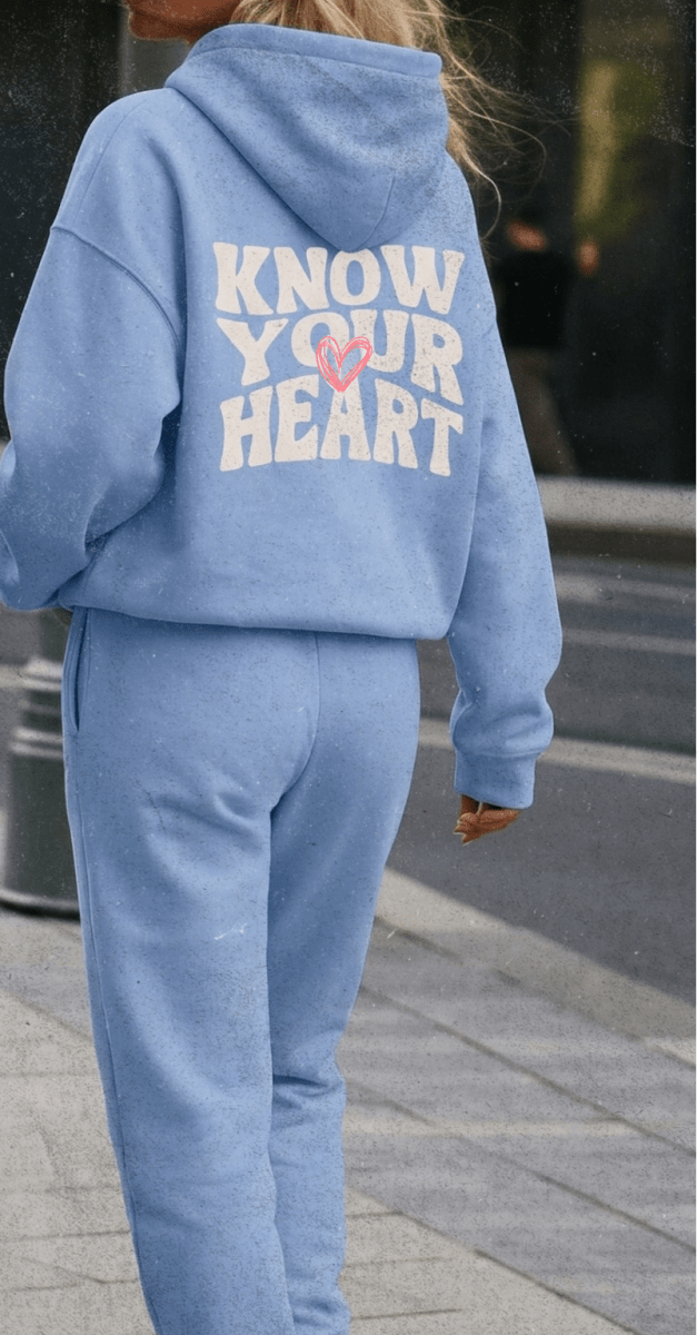 Two people wearing matching tracksuits with 'Know Your Heart' text on the back.