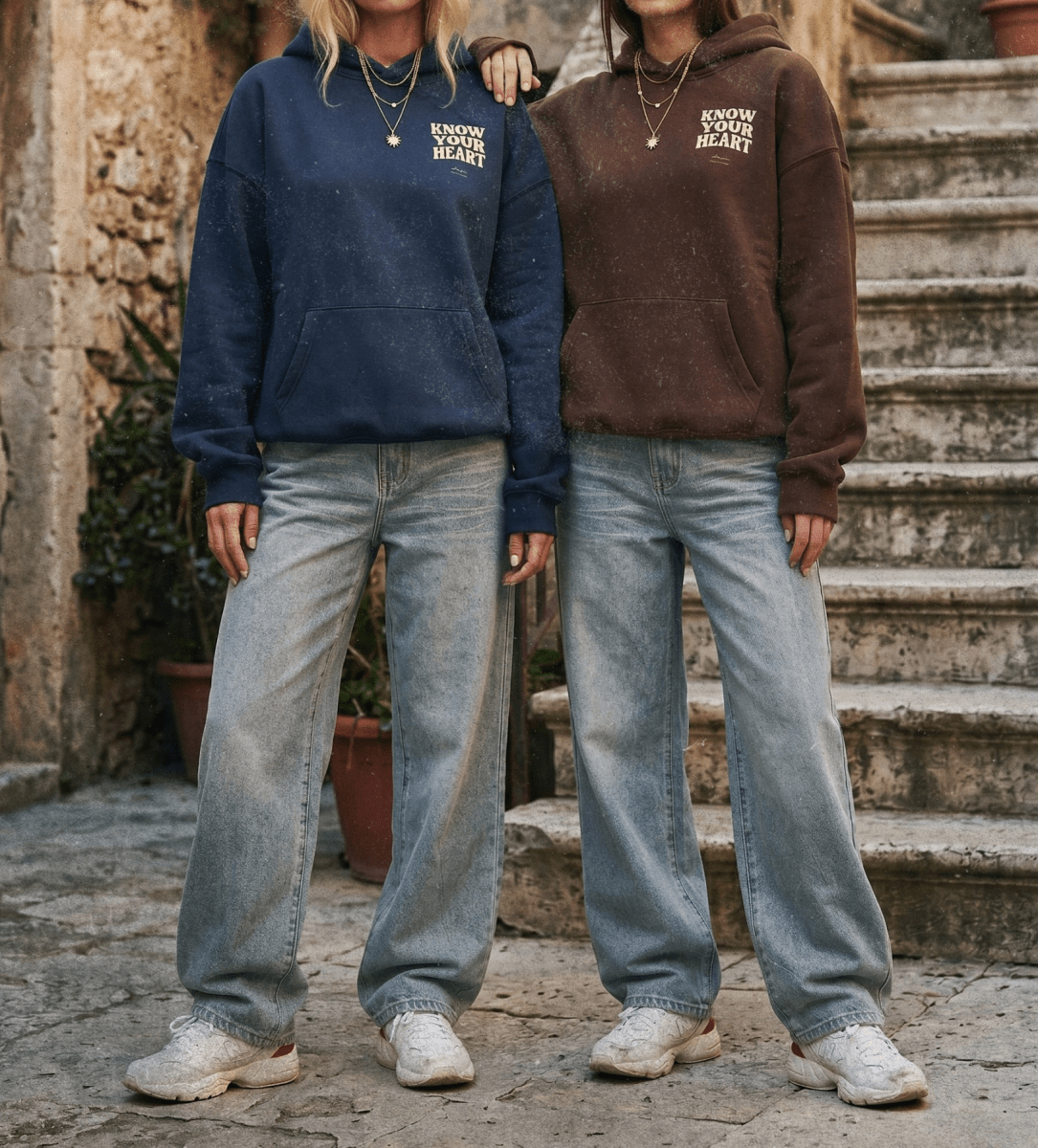 Two people wearing navy and brown hoodies with visible branding, standing on stone steps.