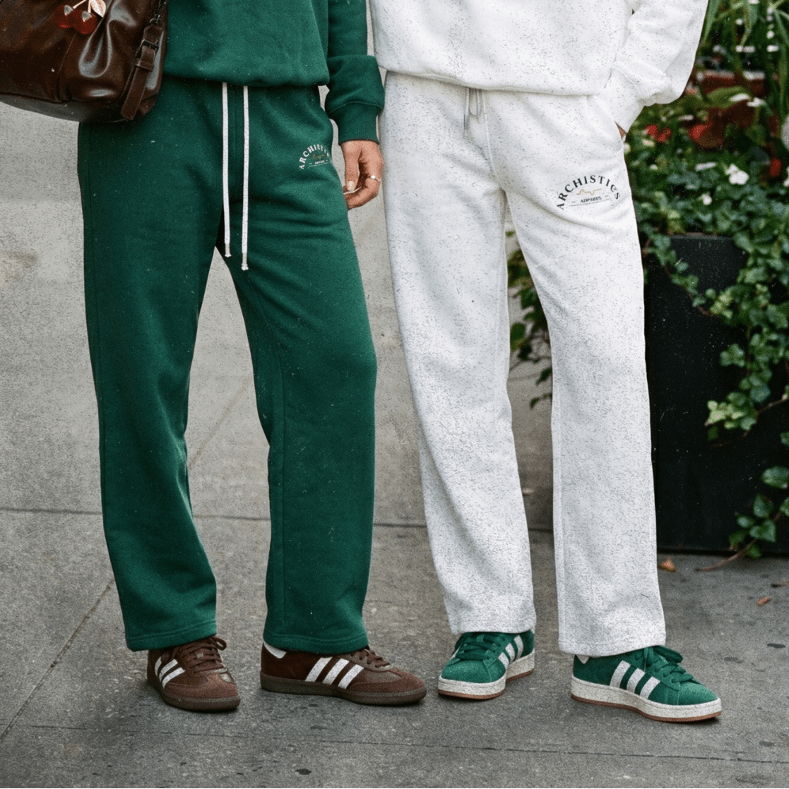 Two women wearing green and white tracksuits with 'Archistics' branding outdoors.
