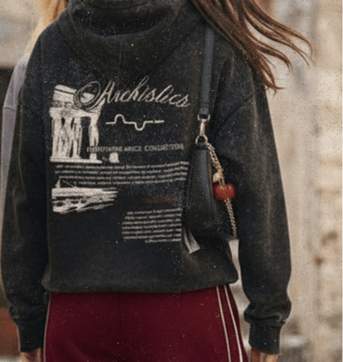Two people walking on a stone street with one wearing a dark hoodie and red pants.